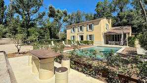 Una casa a due piani con piscina, area salotto esterna e giardino.