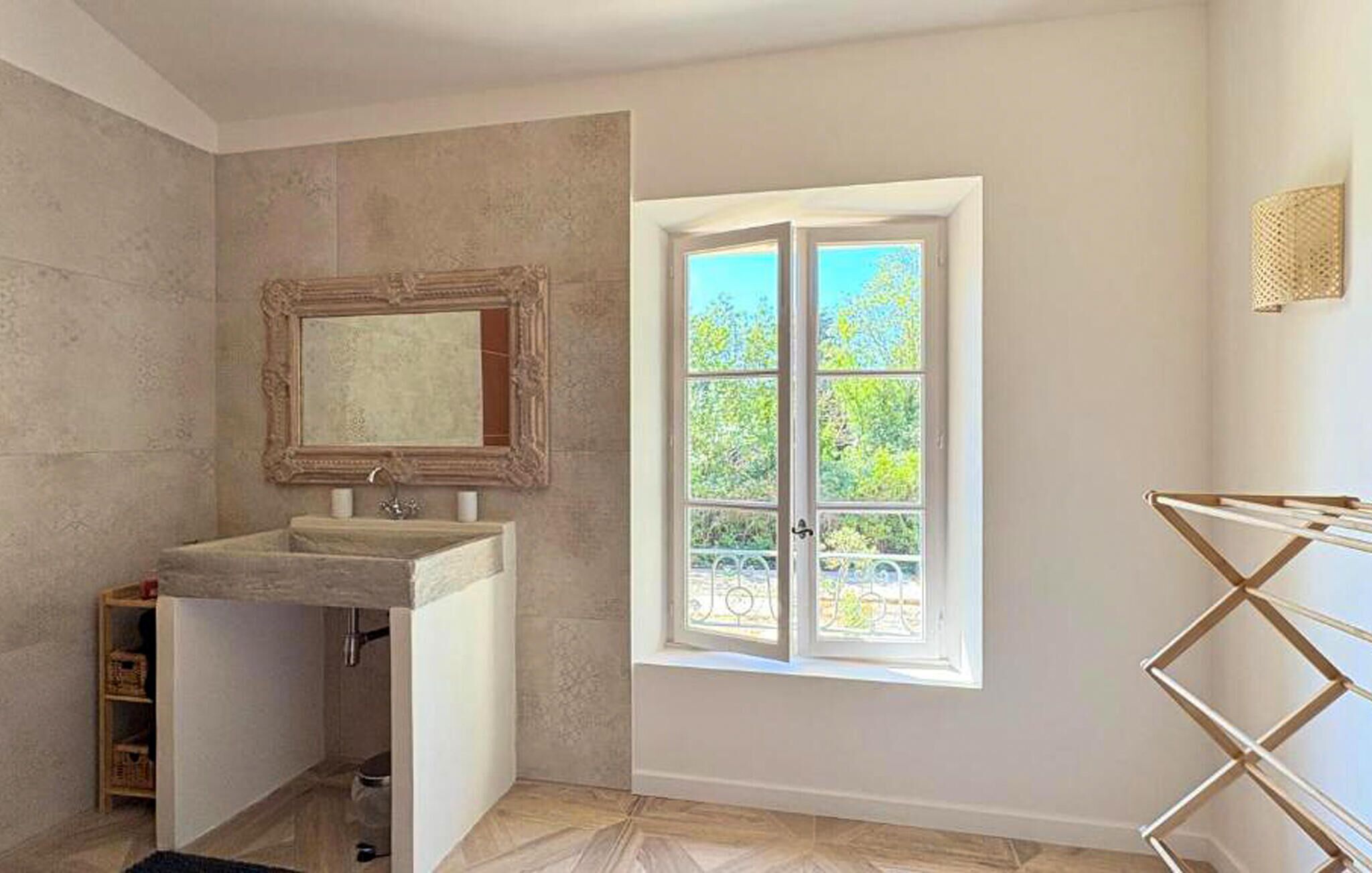 Une salle de bain avec une grande fenêtre, un miroir et un lavabo.