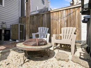 A backyard with a fire pit, two white chairs, and a wooden fence. - Studio Not Far from Capitol Hill, Walk to METRO (Washington)