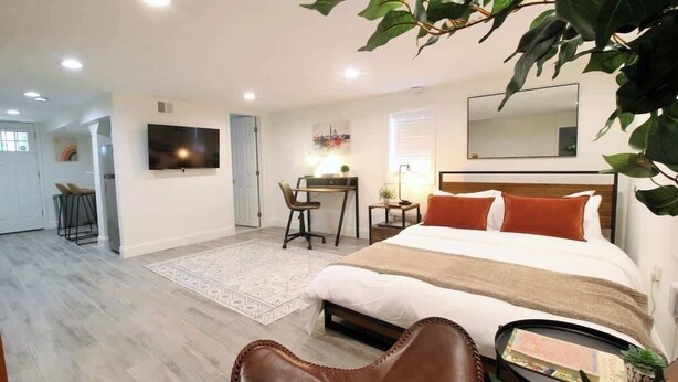 A modern bedroom with a large bed, a desk, and a TV. - Studio Not Far from Capitol Hill, Walk to METRO (Washington)