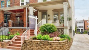A two-story brick building with a white facade, a front porch, and a small garden area. - Studio Not Far from Capitol Hill, Walk to METRO (Washington)