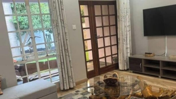 A living room with a sofa, a coffee table, and a television. - Experience comfort & luxury in this stylish villa  in Area 10, lilongwe (Lilongwe)