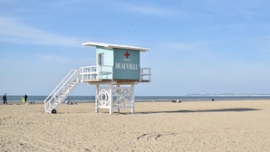 Une tour de surveillance des sauveteurs portant l’inscription « Secours Deauville » se dresse sur une plage sous un ciel dégagé.