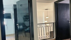 A hallway with a glass door, a black door, and a staircase with a metal railing. - Au Riad des Sultans - Marrakech (Marrakech)