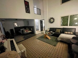 Ein Wohnzimmer mit einer Couch, einem Couchtisch, einem Klavier und einem gemusterten Teppich.