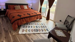 Een slaapkamer met een bed, bureau, stoel, plafondventilator en raam met gordijnen.