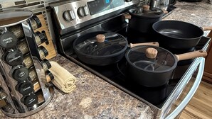 Een keuken met een roestvrijstalen fornuis, een koffiezetapparaat en een waterkoker op het aanrecht.