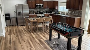 Een moderne keuken met houten vloer, een tafelvoetbaltafel en ingebouwde apparatuur.