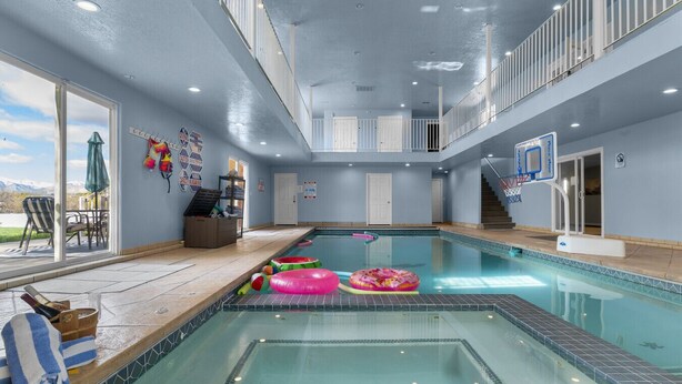 Una piscina interior con aro de baloncesto, una zona de estar junto a la piscina y vistas a la montaña.