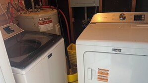 A laundry room with two washing machines, a water heater, and a utility meter. - 2br Albany Corporate Comfort (Albany)
