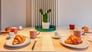 Une table de petit-déjeuner avec des croissants, des tasses de café et une petite plante en pot.