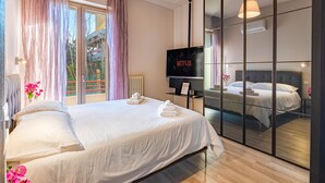Une chambre d’hôtel moderne avec un grand lit, une télévision et une porte-fenêtre coulissante donnant sur le balcon.