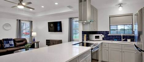 A modern kitchen with a central island, stainless steel appliances, and a ceiling fan.
