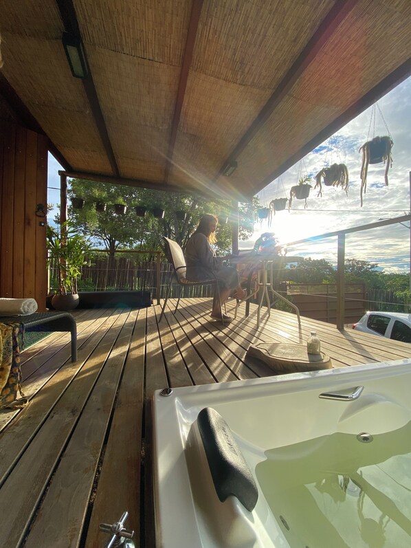 A wooden deck with a hot tub, potted plants, and a view of the sky.