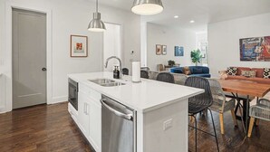 Een moderne keuken met een centraal eiland, roestvrijstalen apparatuur en hanglampen.