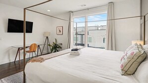 Een moderne slaapkamer met een hemelbed, een bureau en een televisie aan de muur.