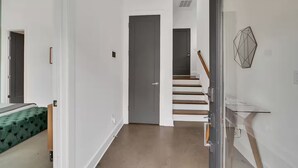 Et moderne interiør med trappe, dør og gelænder i glas.