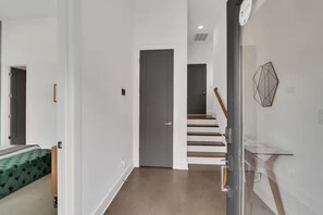 A modern interior with a staircase, a door, and a glass railing. - Skyline Rooftop | Sleeps 12 | 10 Min to Broadway (Nashville)