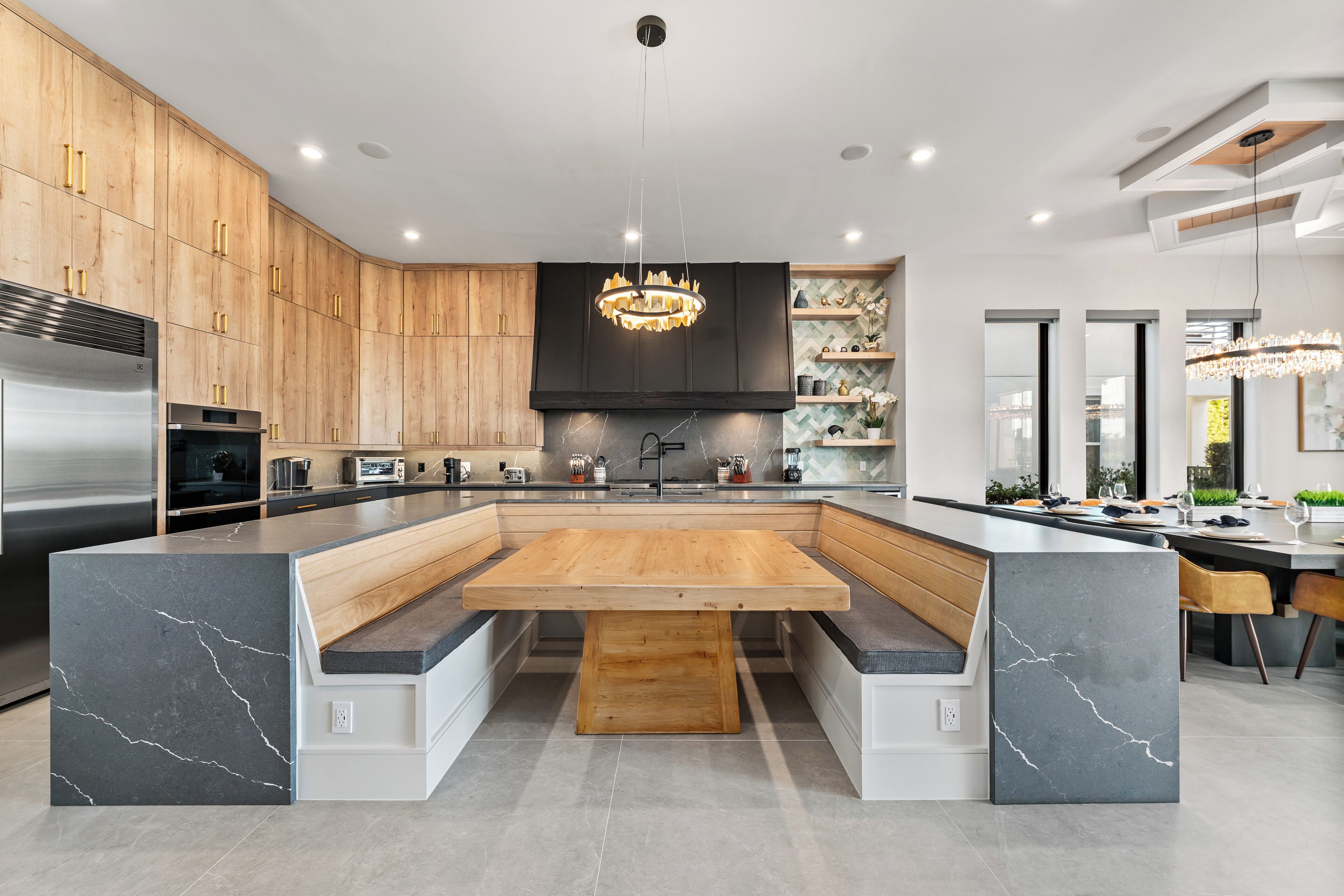 A modern kitchen with a central island, wooden cabinets, and a marble countertop.