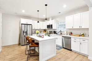 A modern kitchen with white cabinets, stainless steel appliances, and a central island with seating. - Charming 3 BDR Bungalow - Prime DT ATL Location! (Atlanta)