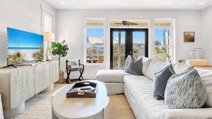 A living room with a large TV, a sofa, a coffee table, and a ceiling fan. - Resting Beach Place by Stay on 30a (Seacrest Beach)