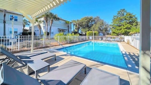 A swimming pool with lounge chairs, a pergola, and a fenced pool area. - Resting Beach Place by Stay on 30a (Seacrest Beach)