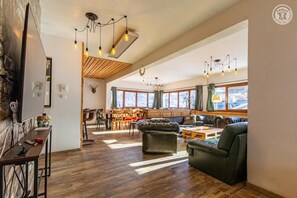 A spacious living area with a wooden ceiling, a dining area with a wooden table and chairs, and a seating area with leather sofas. - L'annexe Des Chalets De L'armera (VALMEINIER)