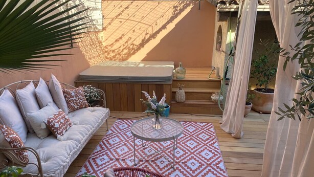 A cozy outdoor seating area with a sofa, patterned rug, and a hot tub. - Maison Flammarion - Welkeys (Avignon)