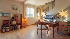 A well-lit room with a wooden desk, bookshelves, a computer, and a large mirror. - Maison Flammarion - Welkeys (Avignon)