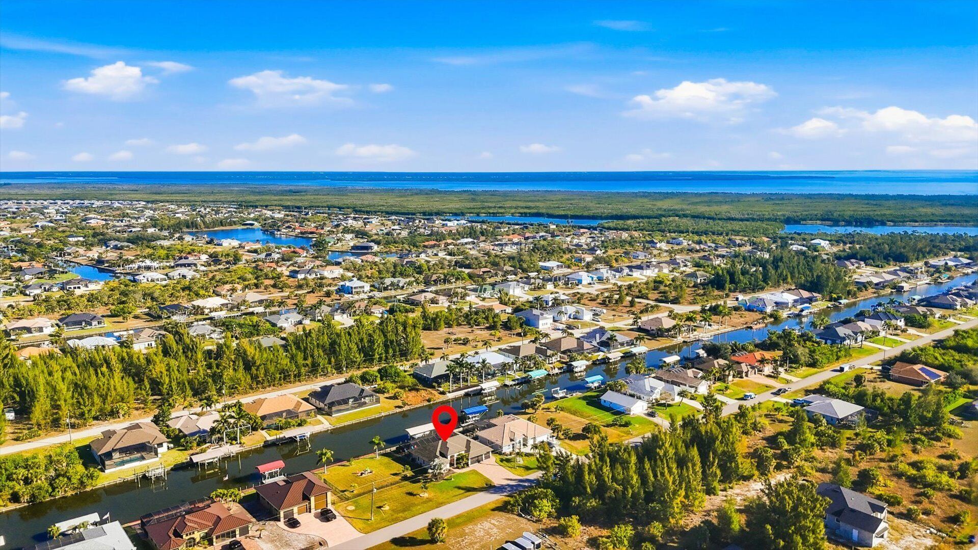 Luchtbeeld van een woongebied met huizen en een meer, met een rode markering voor de locatie.