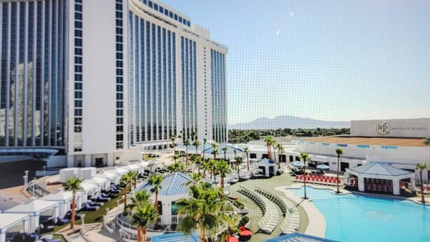 A resort with a large pool, palm trees, and a high-rise building in the background. - Luxury Experience-4BR Villa-10 people-Las Vegas Resort & Casino-Ideal for Groups (Las Vegas)