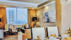 A hotel room with a large window, a sofa, a dining table with a vase of flowers, and a chandelier. - Luxury Experience-4BR Villa-10 people-Las Vegas Resort & Casino-Ideal for Groups (Las Vegas)