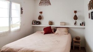 Ein Schlafzimmer mit einem Bett, einem Nachttisch, einem Regal mit Dekoration und einem Fenster.