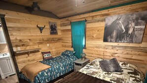 A rustic wooden room with a bed, a bench, a ceiling fan, and a wall-mounted picture. - Sinopah #5 (East Glacier Park)