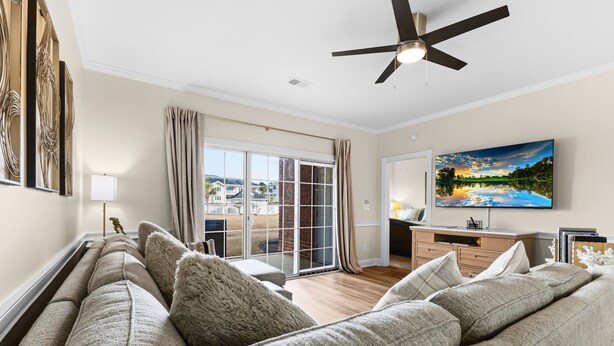 Ein Wohnzimmer mit einer Couch, einem Deckenventilator, einem Fernseher und einem Gemälde.