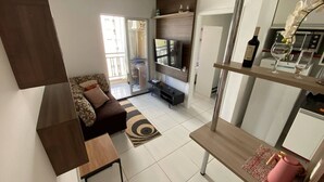 Una sala moderna con sofá, televisor y un comedor con mesa y sillas.