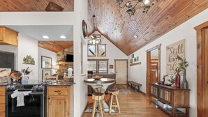 A spacious kitchen with a central island, wooden ceiling, and a dining area with stools.