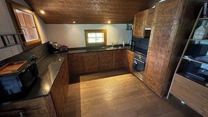 Eine moderne Küche mit Holzschränken, einer schwarzen Arbeitsplatte und einer zentralen Kochinsel.