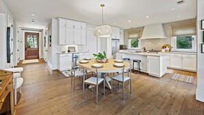 A modern kitchen with white cabinetry, a round dining table with chairs, and a hanging light fixture. - Stunning Marsh Views! Plunge Pool, Quiet Kiawah 3BR Home! (Kiawah Island)