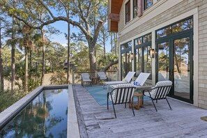Eine Terrasse mit Pool, Gartenmöbeln und Blick auf die umliegenden Bäume.
