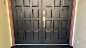 En dubbeldörr med ett kodlås, placerad i en beige vägg med en kakelbeklädd entré.