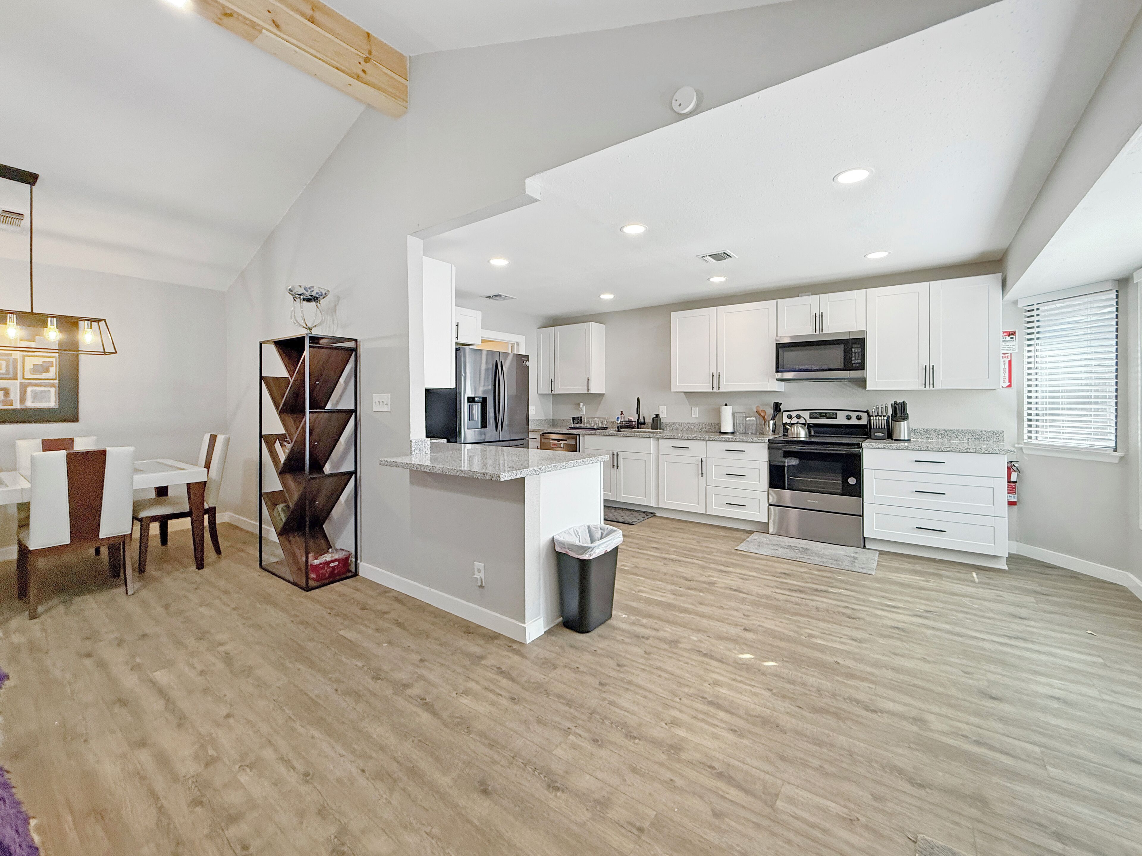 Une cuisine moderne avec des armoires blanches, des appareils en acier inoxydable et un plancher en bois.