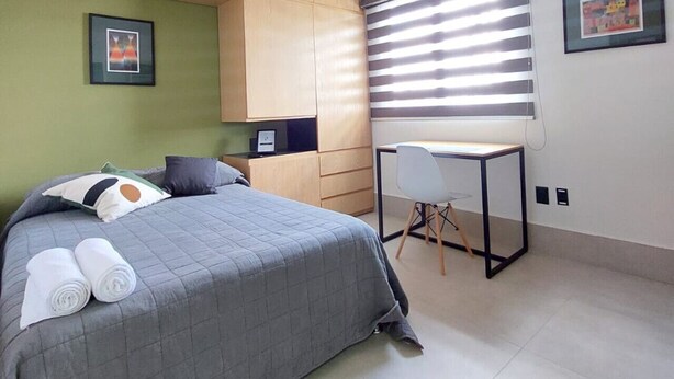 A bedroom with a bed, a desk, and a chair. There are two framed pictures on the wall. - Tu espacio en Col Americana y AV Chapultepec (Guadalajara)