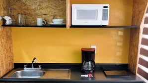 Eine kleine Küche mit Mikrowelle, Spüle und Kaffeemaschine.