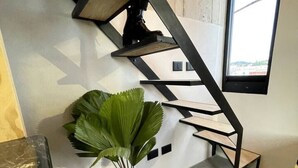 Una escalera de diseño moderno, una planta en maceta y vistas al exterior a través de un ventanal.