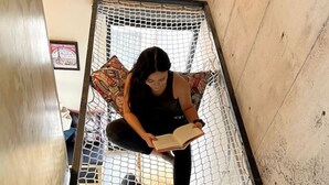 Una persona sentada en una hamaca en una habitación con vistas al exterior.