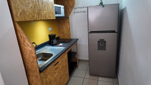 A compact kitchen with a stainless steel refrigerator, a microwave, and a coffee maker on a wooden countertop. - Depa cerca del Paseo Bravo (Puebla)