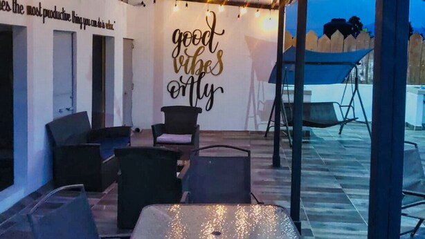 An outdoor patio with string lights, a table, chairs, and a wall with motivational writing. - Depa cerca del Paseo Bravo (Puebla)