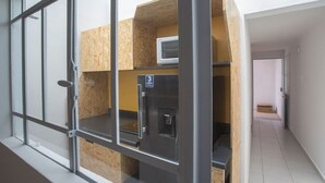 A modern interior with a kitchenette area, a microwave, and a refrigerator. - Depa cerca del Paseo Bravo (Puebla)