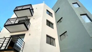 Un edificio moderno con facciata bianca, diversi balconi e un'ampia porta garage.